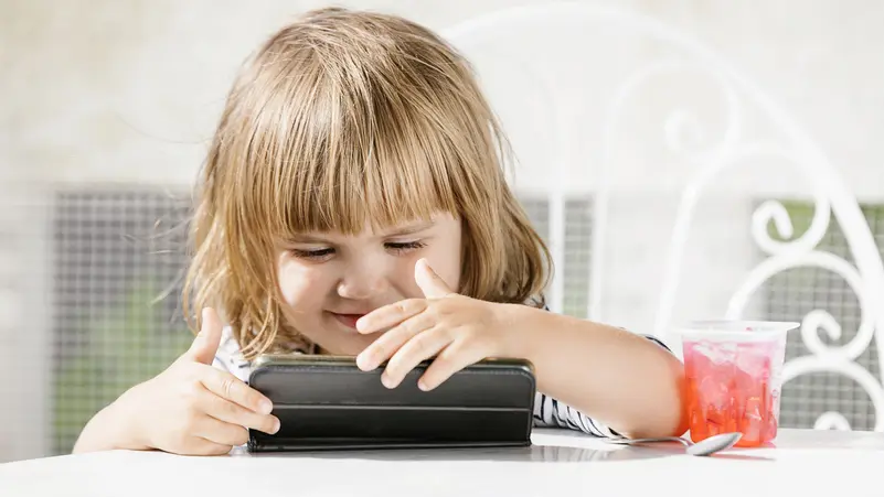 طفلة تشاهد محتوى على هاتف ذكي