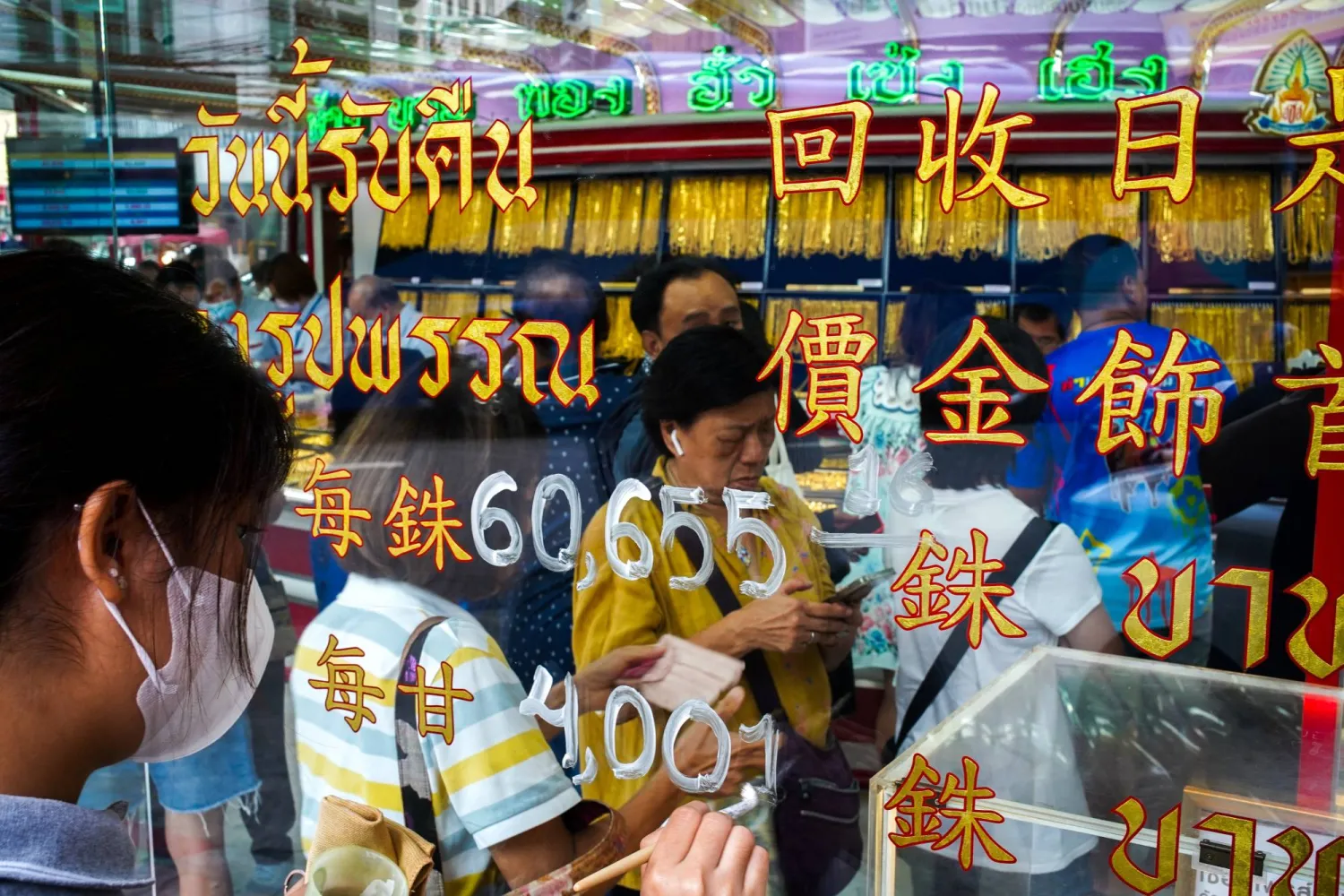 أحد الموظفين يقوم بتحديث أسعار الذهب بينما يصطف الزبائن داخل متجر للذهب في الحي الصيني ببانكوك