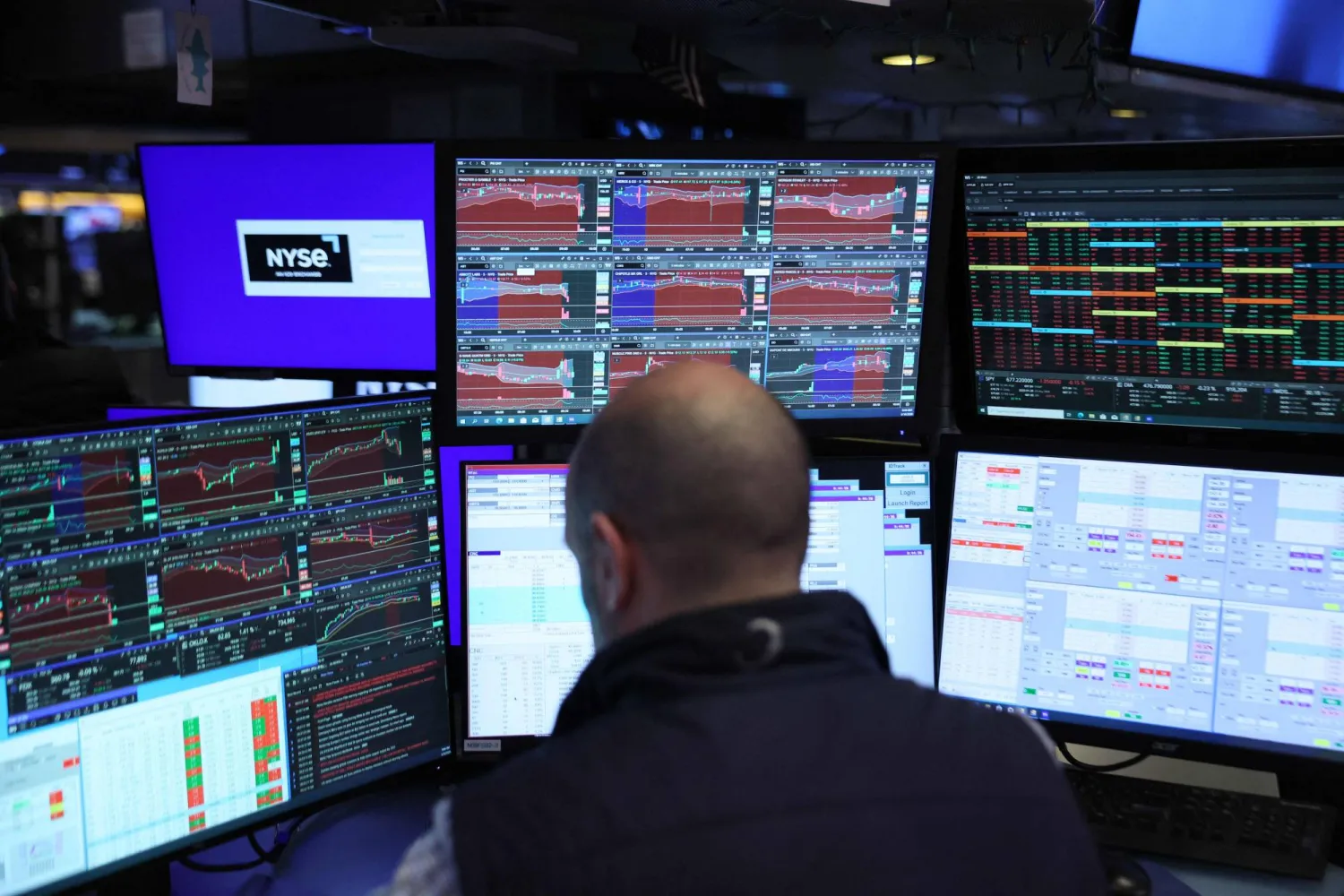 متداول يراقب شاشات تعرض مؤشرات الأسهم في بورصة نيويورك
