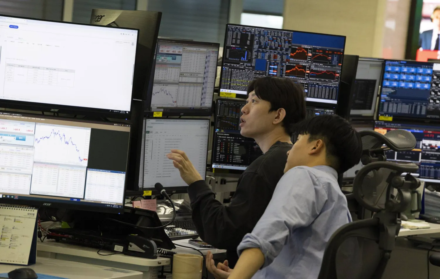 متداولون كوريون جنوبيون يعملون أمام شاشات تعرض مؤشرات الأسهم في بنك هانا في سيول